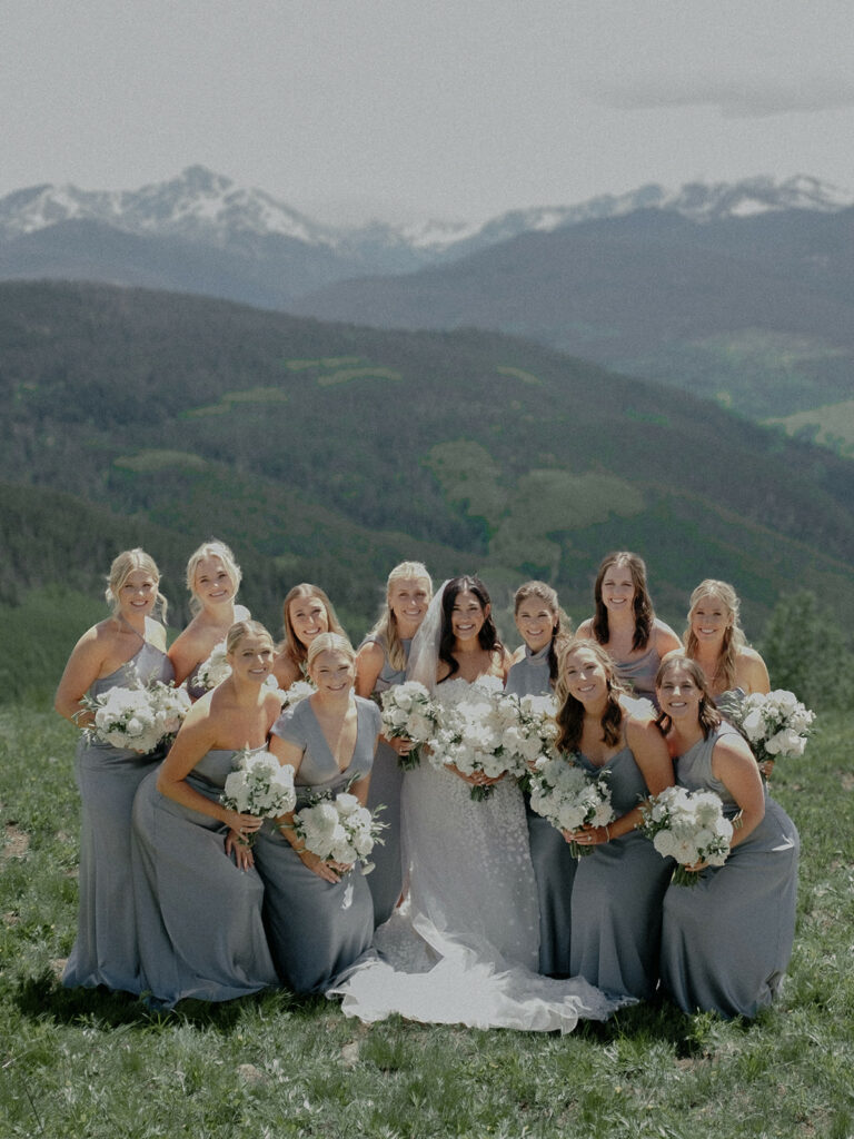 Bride and bridesmaids posing outdoors in mountains.