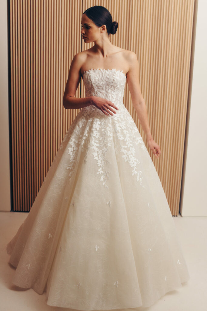 Woman in ivory strapless ball gown before wood panels.