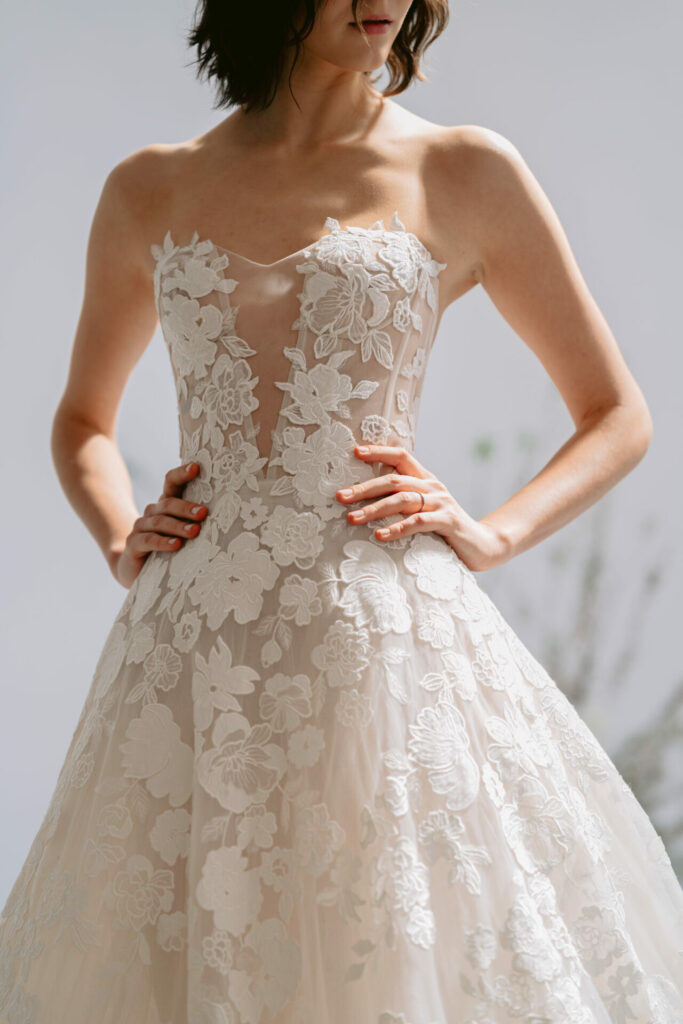 Woman poses in sheer, floral lace wedding gown.