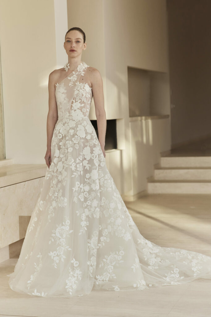 Bride in white lace halter gown with train indoors.