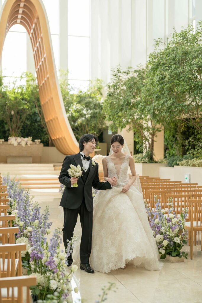 Bride and groom walk aisle in bright, modern venue.