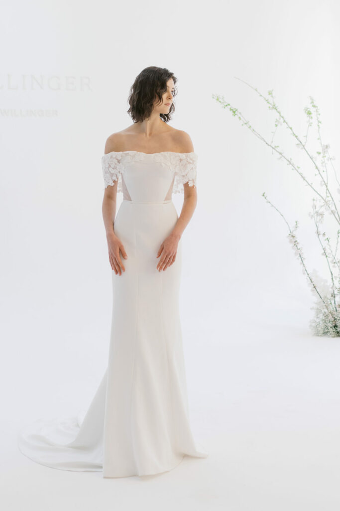 Bride in lace wedding dress in bright, floral room.