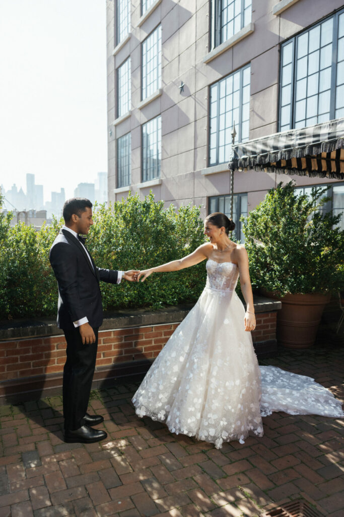 Bride and groom smiling, holding hands on patio.