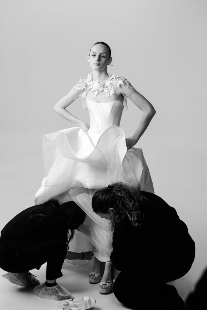 Model in floral-shouldered white dress, hem adjusted.