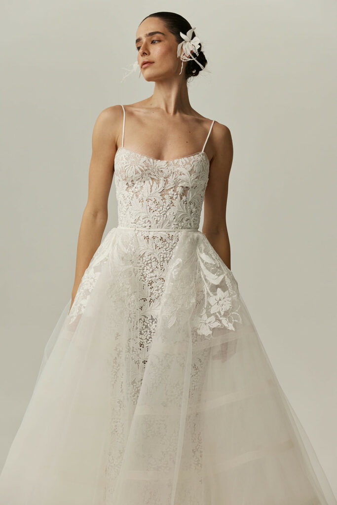 Bride in white lace gown with floral hairpiece.