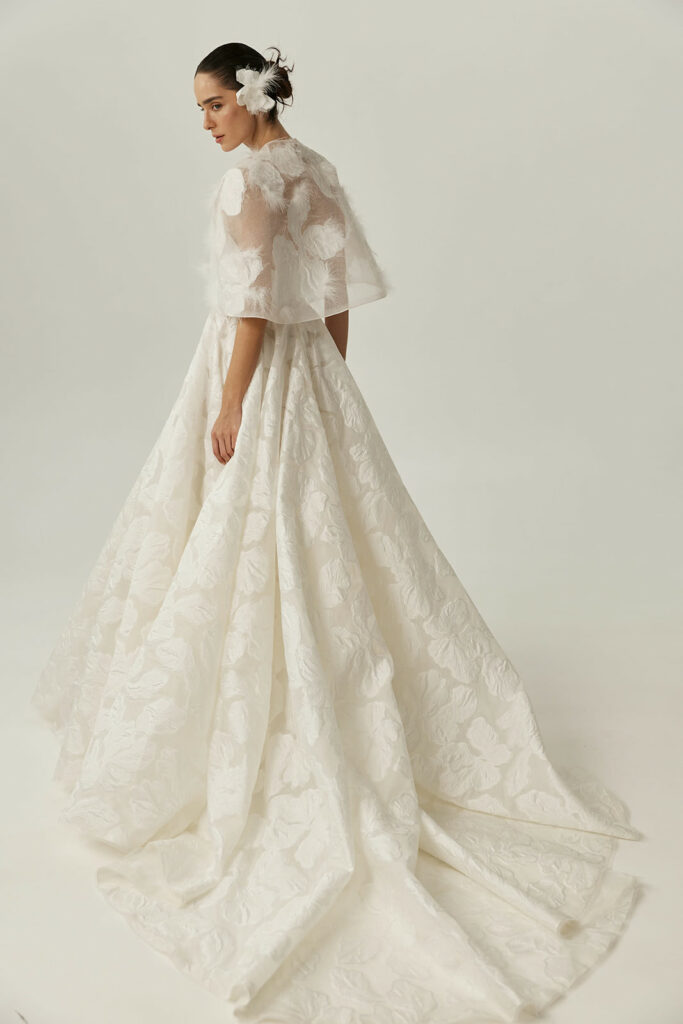 Woman in floral white gown, hair with flower.