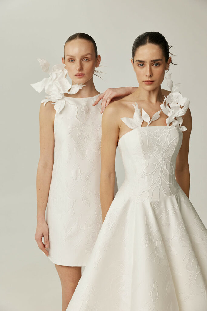 Two women model white floral dresses, neutral expressions.