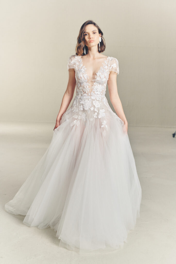 Woman in sheer white floral gown in bright room.
