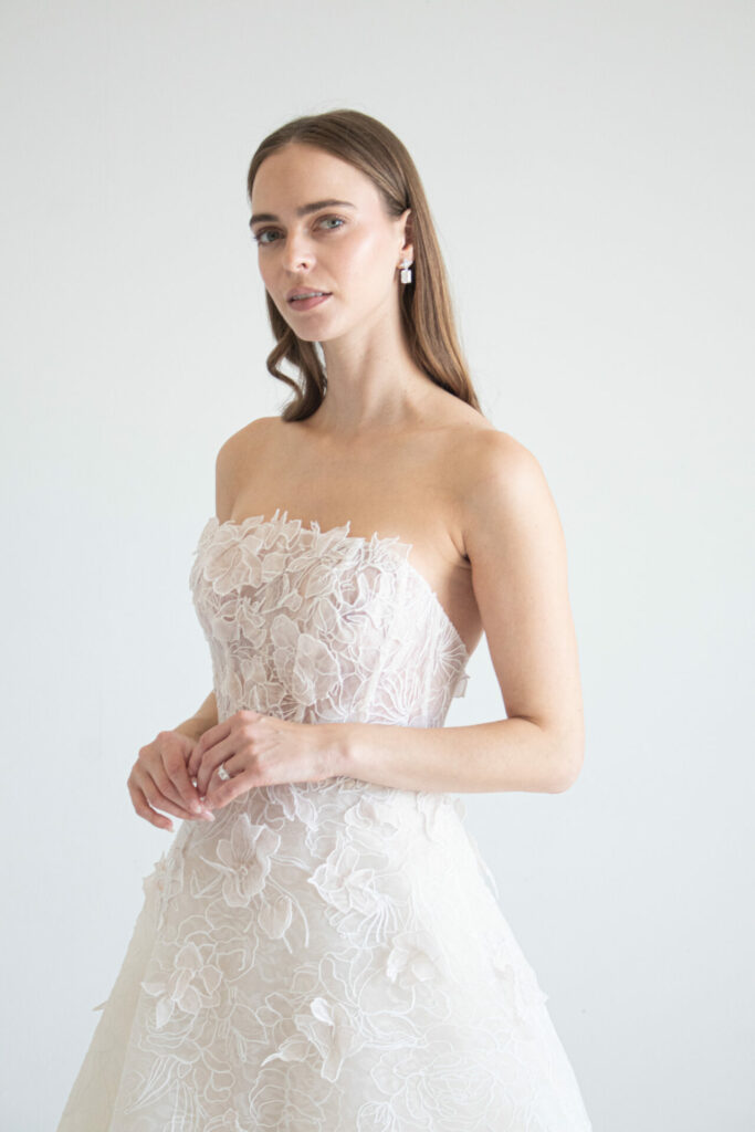Woman in white floral dress, loose waves, side glance.