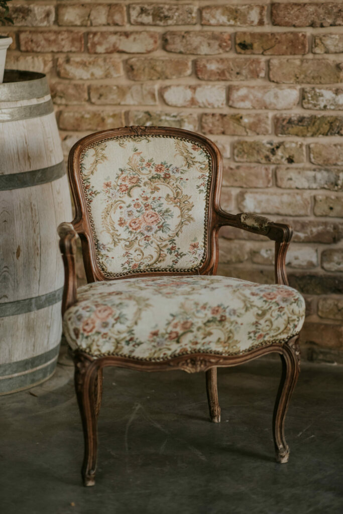 Vintage floral armchair and barrel on concrete floor.