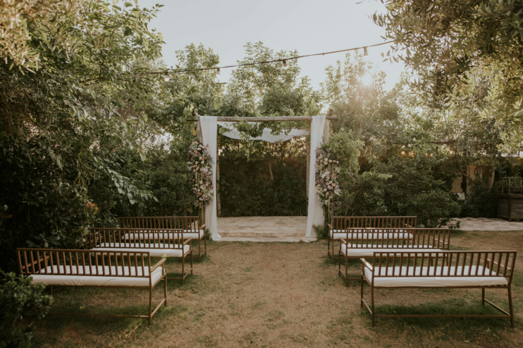 Floral arch and gold benches for outdoor wedding.