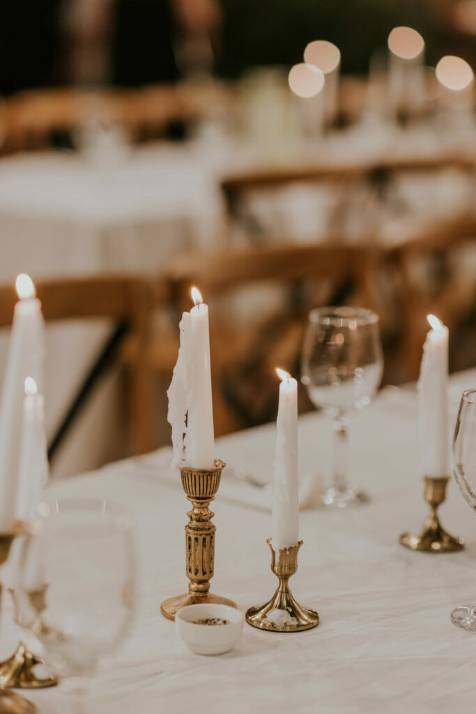 Elegant event table with candles, wine glasses, white cloth.
