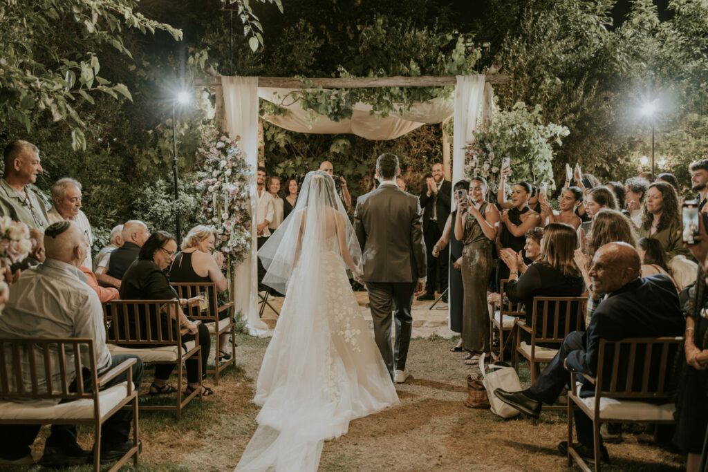 Bride Katya Ruiz and groom walk under lit canopy.