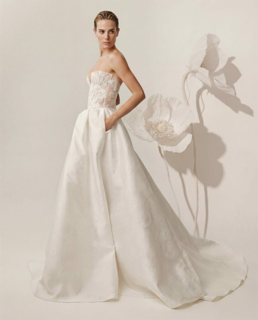 Woman in strapless white bridal gown, paper flowers behind.