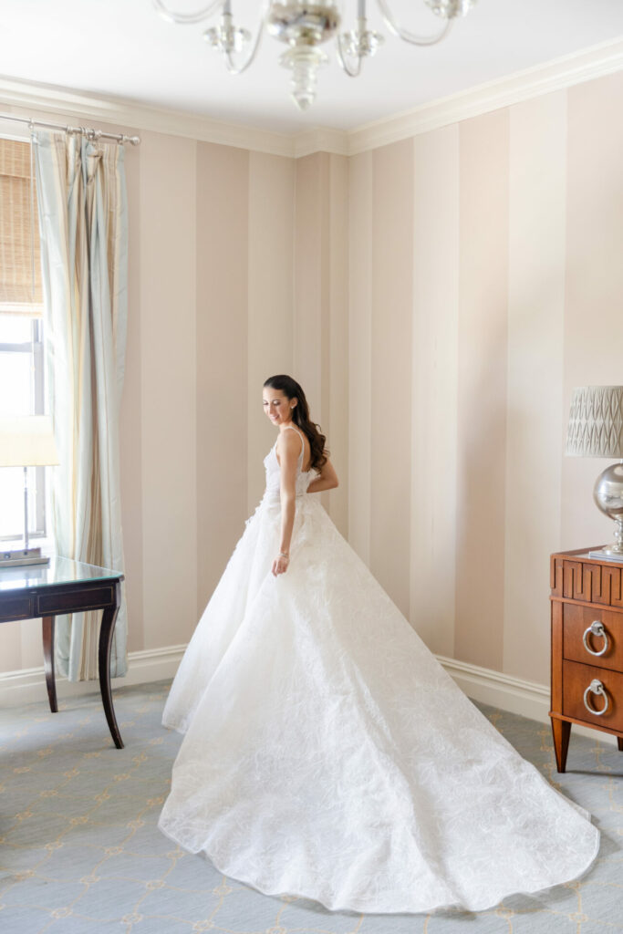Katya Ruiz in white gown smiles over shoulder.