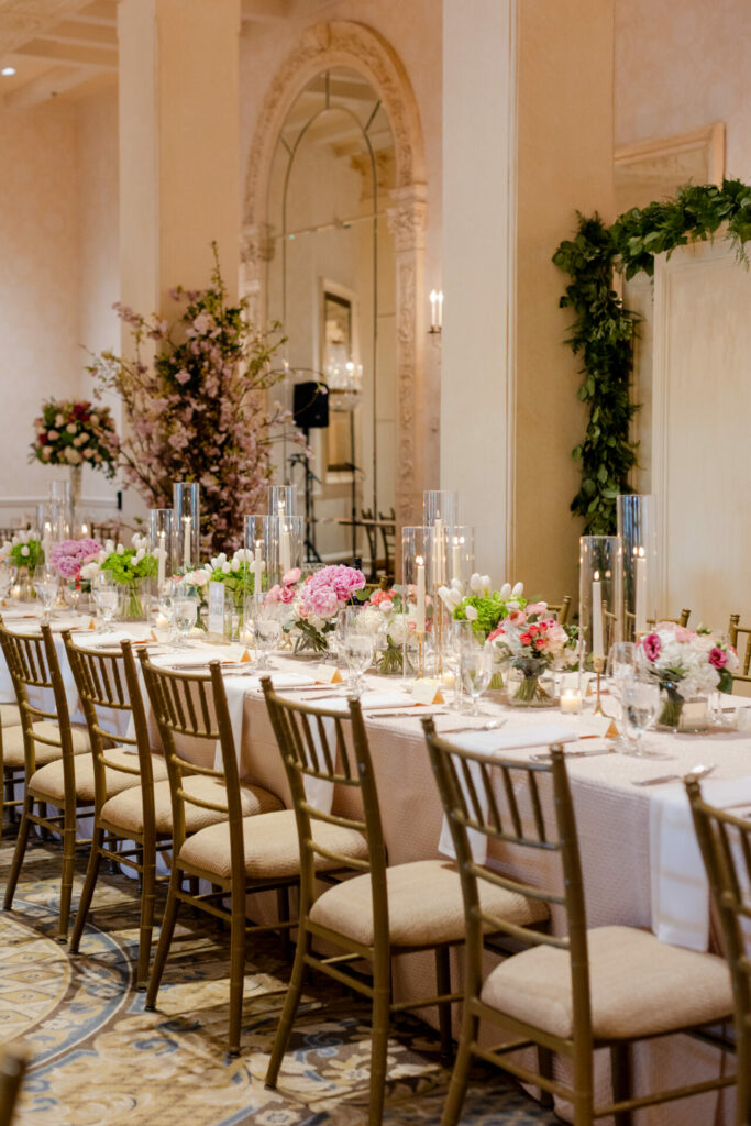 Elegant table with florals, candles, greenery in ornate room.