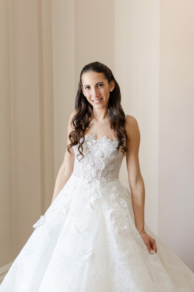 Katya Ruiz smiles in a strapless, floral lace wedding gown.