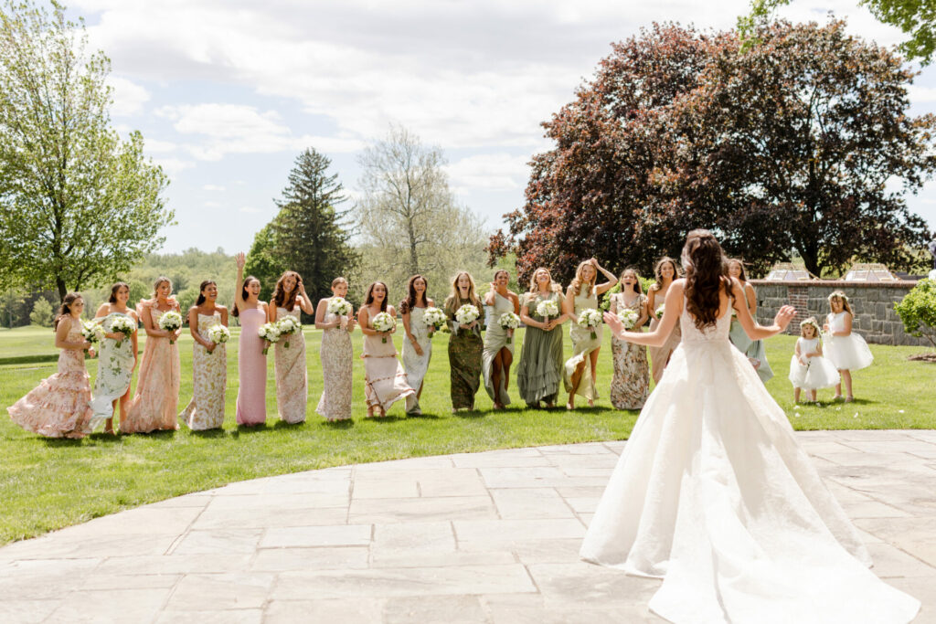 Katya Ruiz in bridal gown faces bridesmaids outdoors.