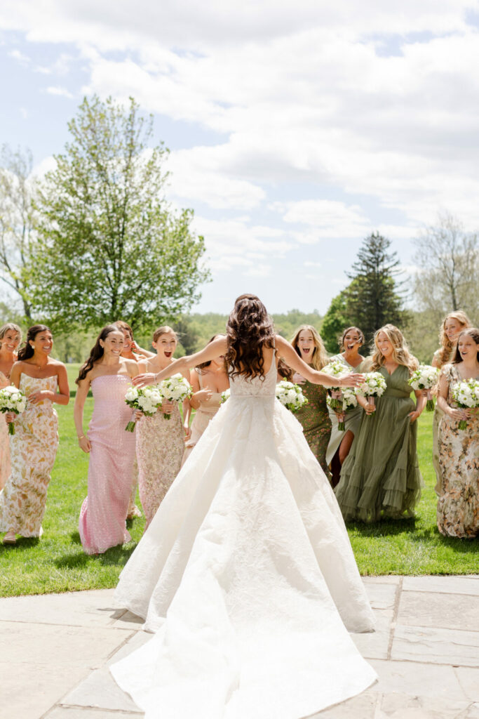 Katya Ruiz in Mira Zwillinger gown greets bridesmaids outdoors.
