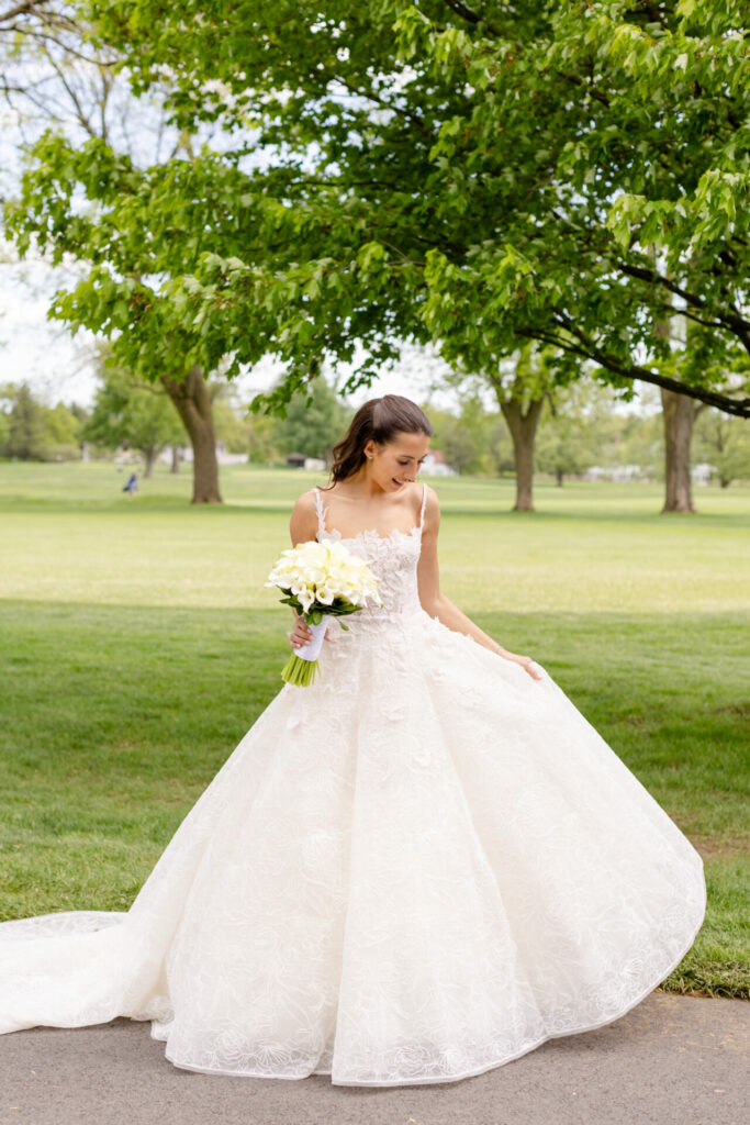Katya Ruiz outdoors in floral bridal gown, bouquet in hand.