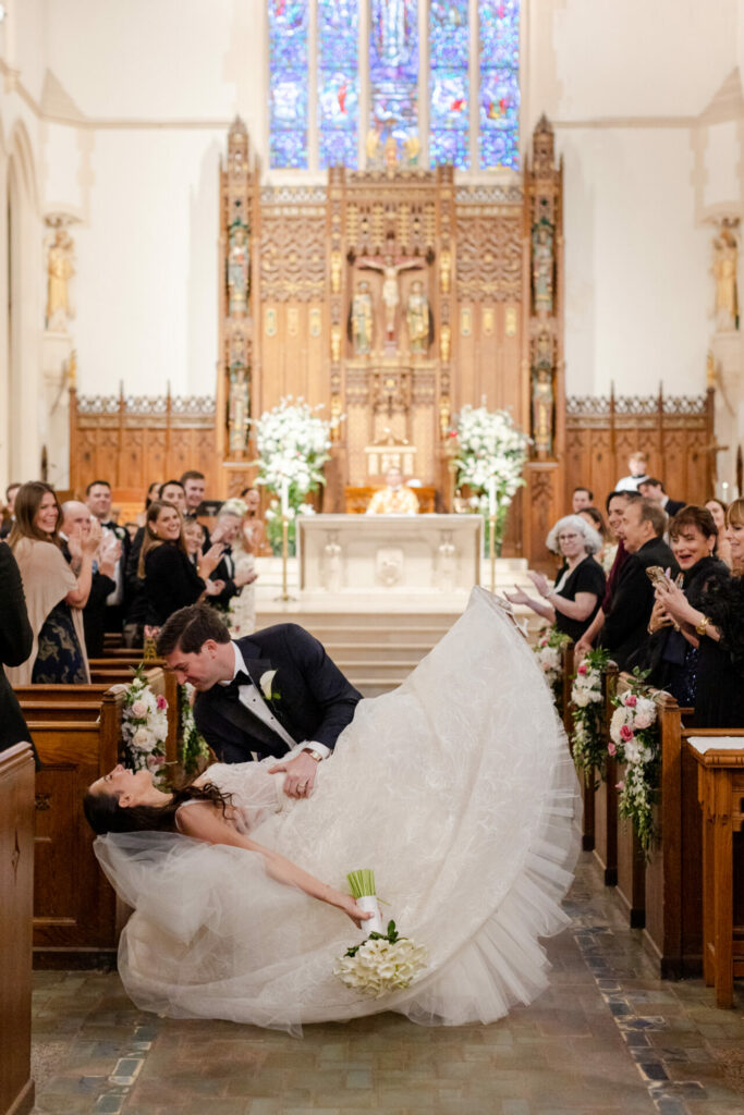 Groom dips Katya Ruiz for a kiss; guests clap.