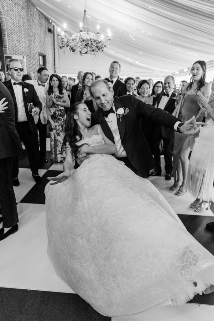 Bride and father dance, joyful guests surround in luxury.