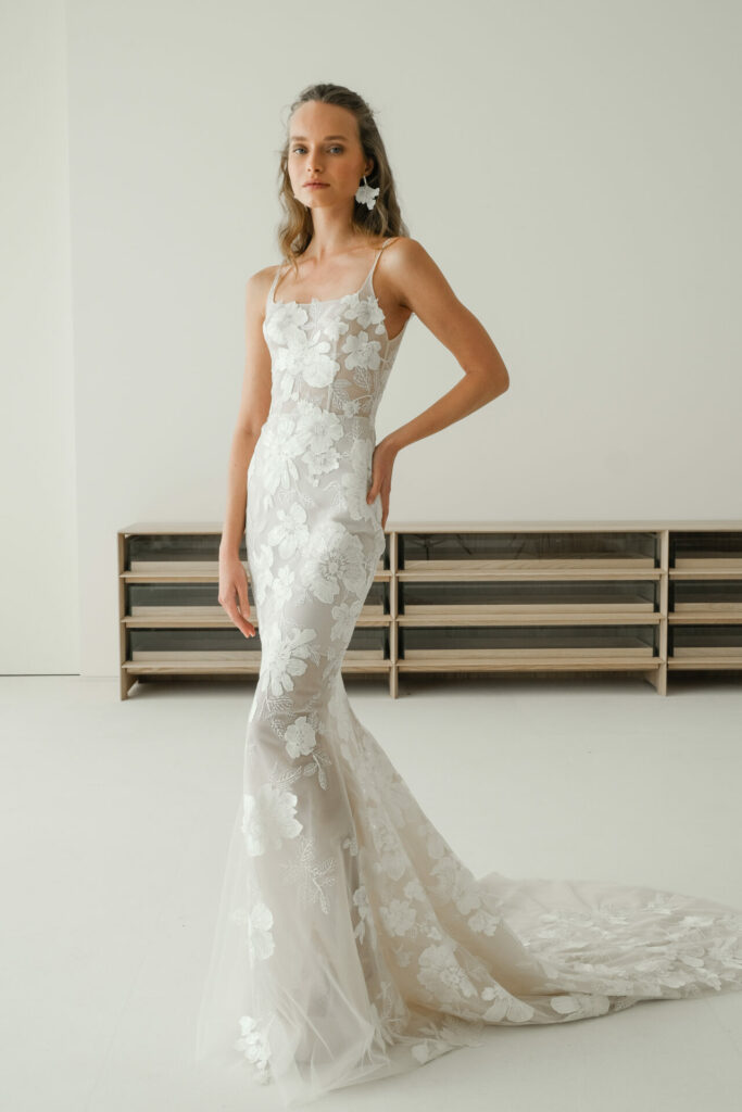 Woman in white lace wedding dress, confident gaze.