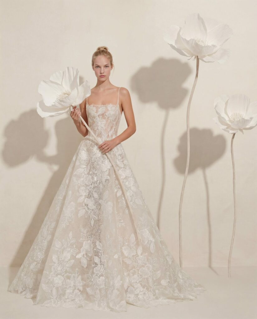 Woman in lace wedding gown holding large paper flower.