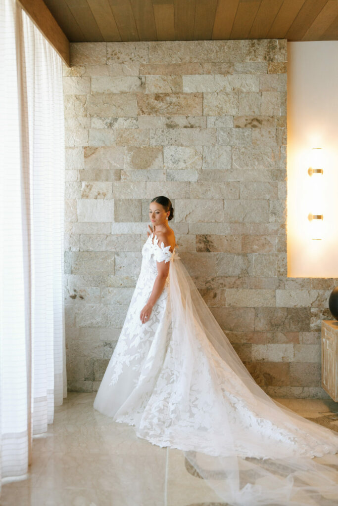 Bride Katya Ruiz in off-shoulder lace gown, serene.