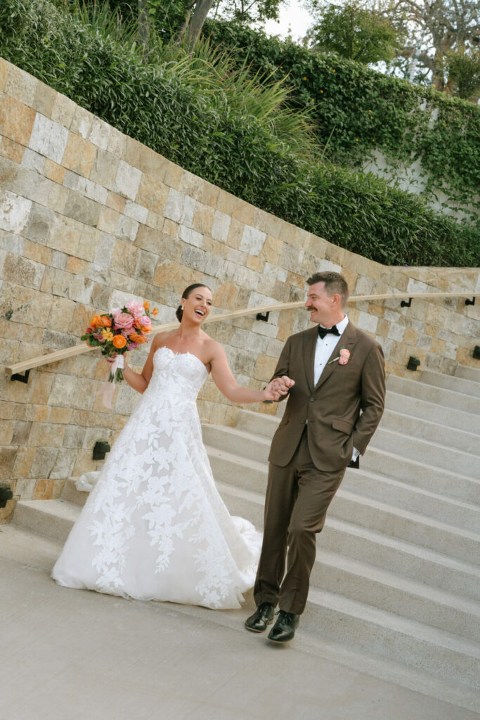 Smiling bride Katya Ruiz and groom walk down steps joyfully.