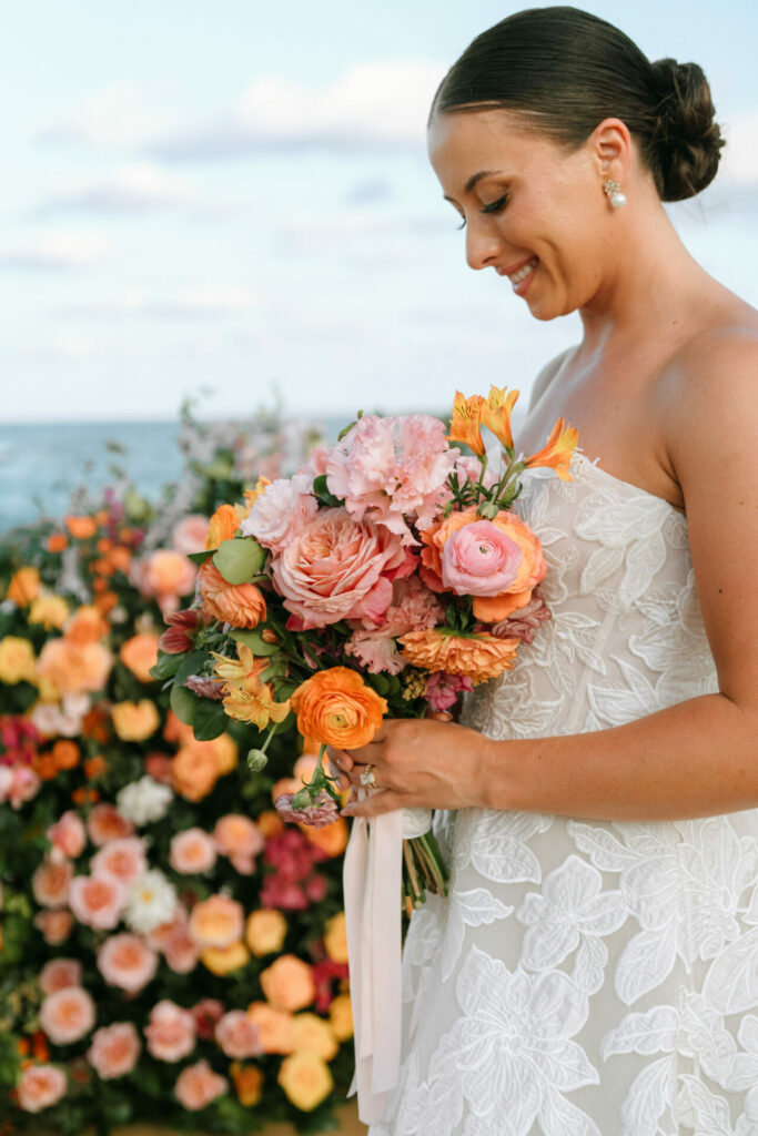 Katya Ruiz in Mira Zwillinger gown, smiling outdoors with bright bouquet.