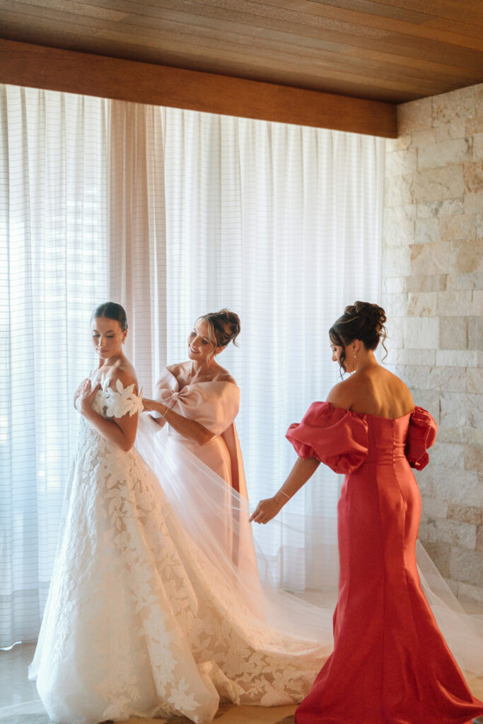 Bride in luxury gown near window, veil adjusted.