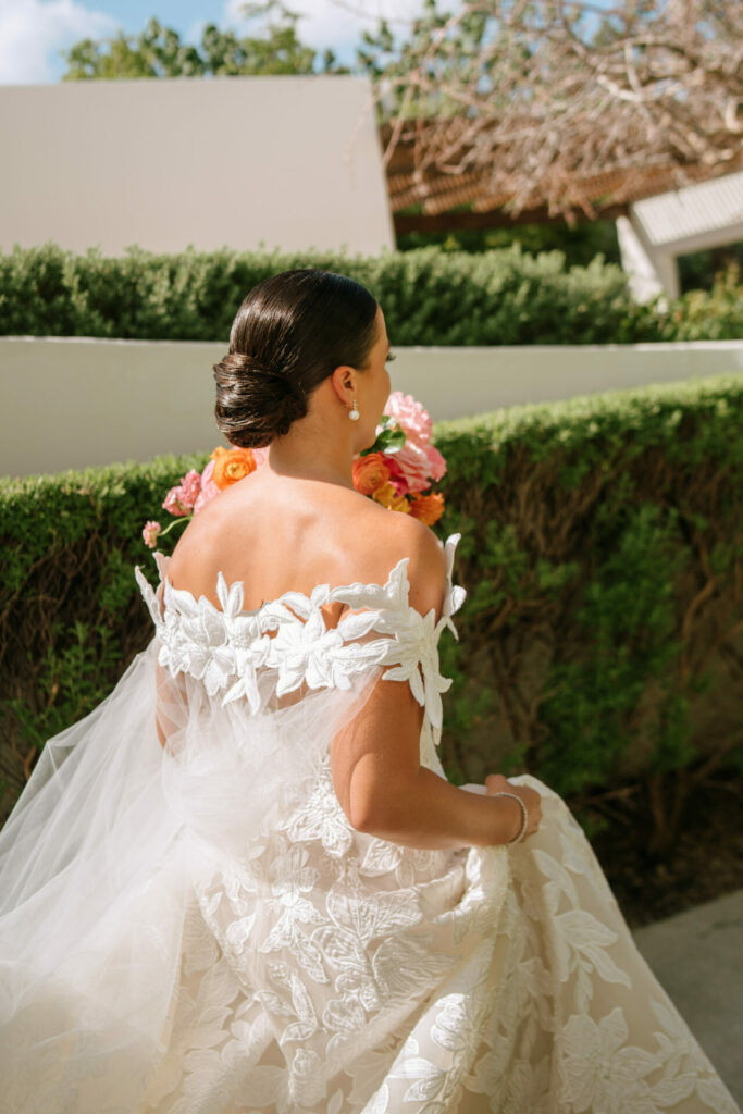 Katya Ruiz in couture gown holding vibrant bouquet outdoors.