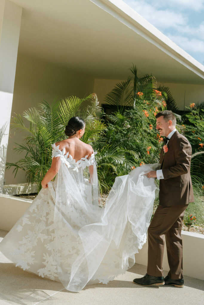 Bride in couture gown, groom helps her outside.