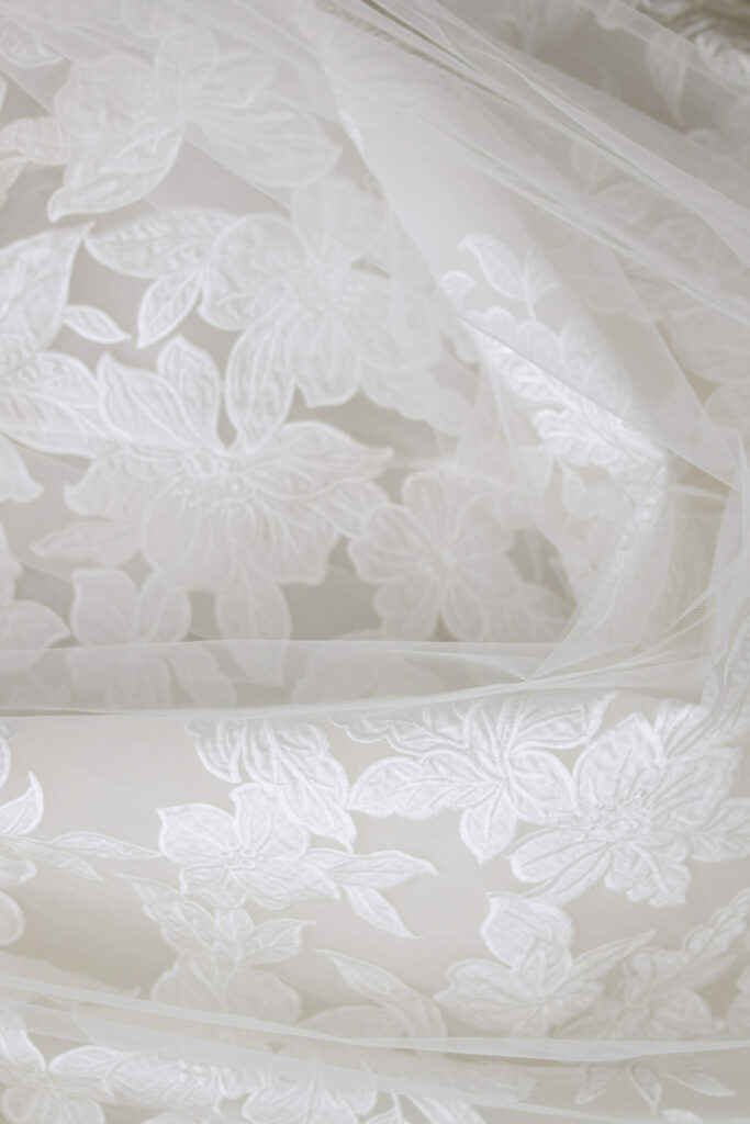 Sheer white fabric, intricate floral pattern, airy layers.