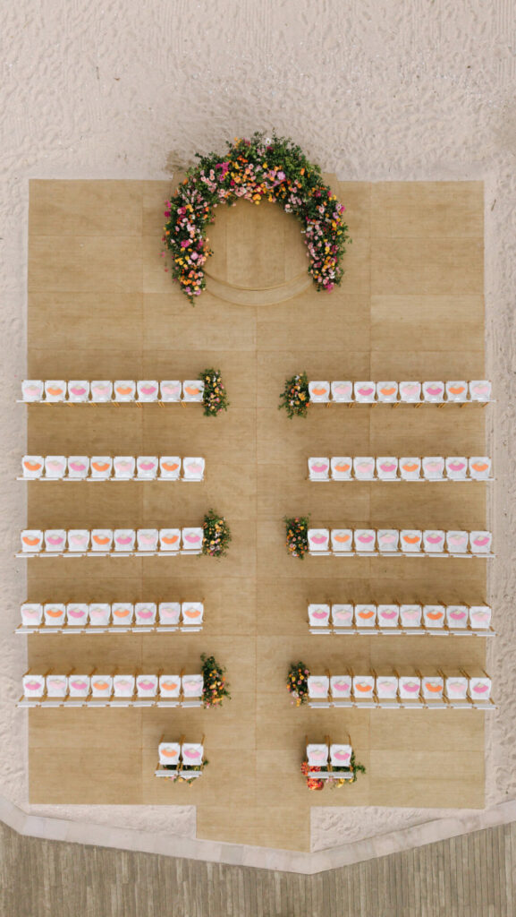 Elegant beach wedding setup with colorful chairs and arch.
