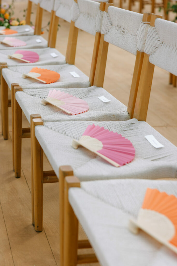 Wooden chairs with colorful fans and name cards.