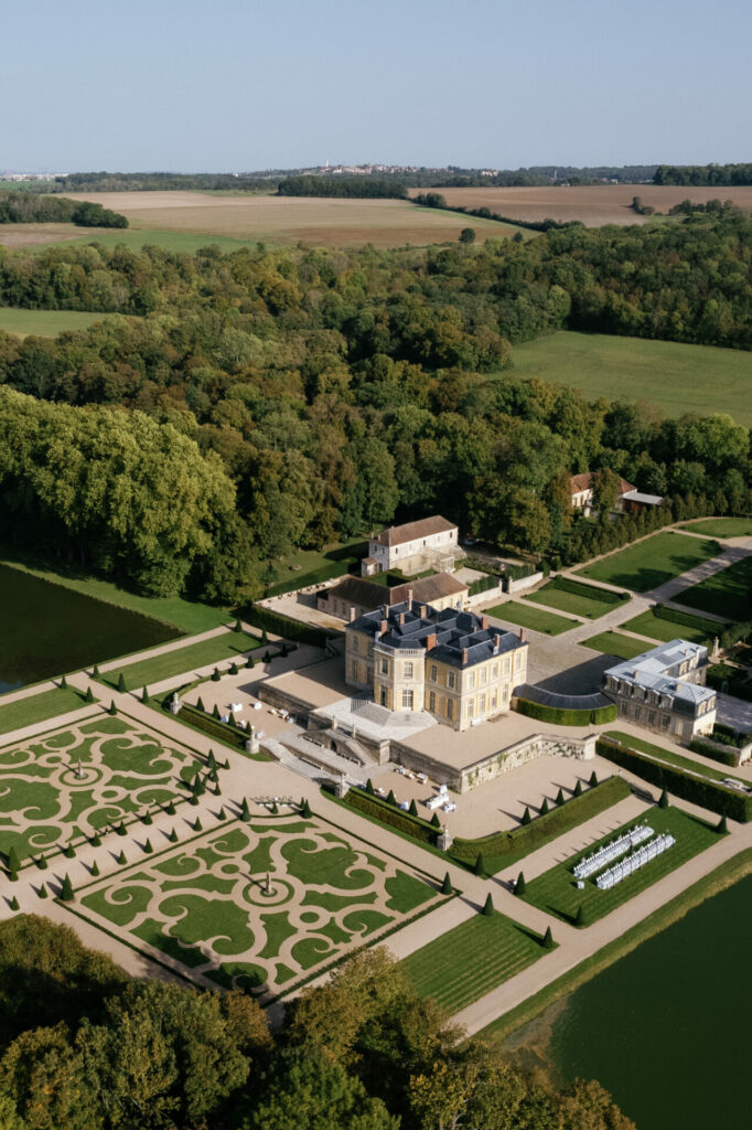 Grand chateau, formal gardens, reflecting ponds amid greenery.