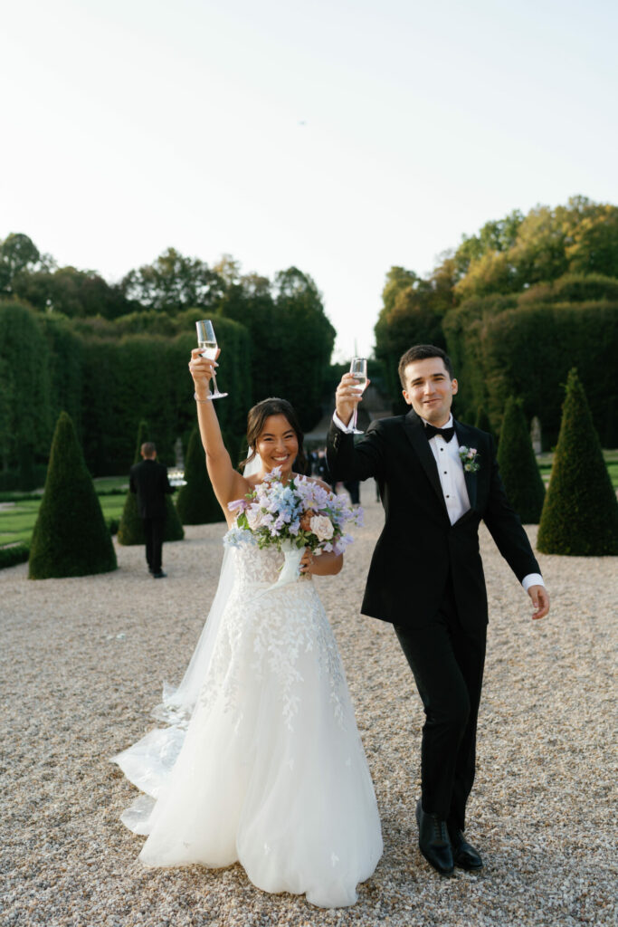 Bride and groom toast outdoors in couture attire.