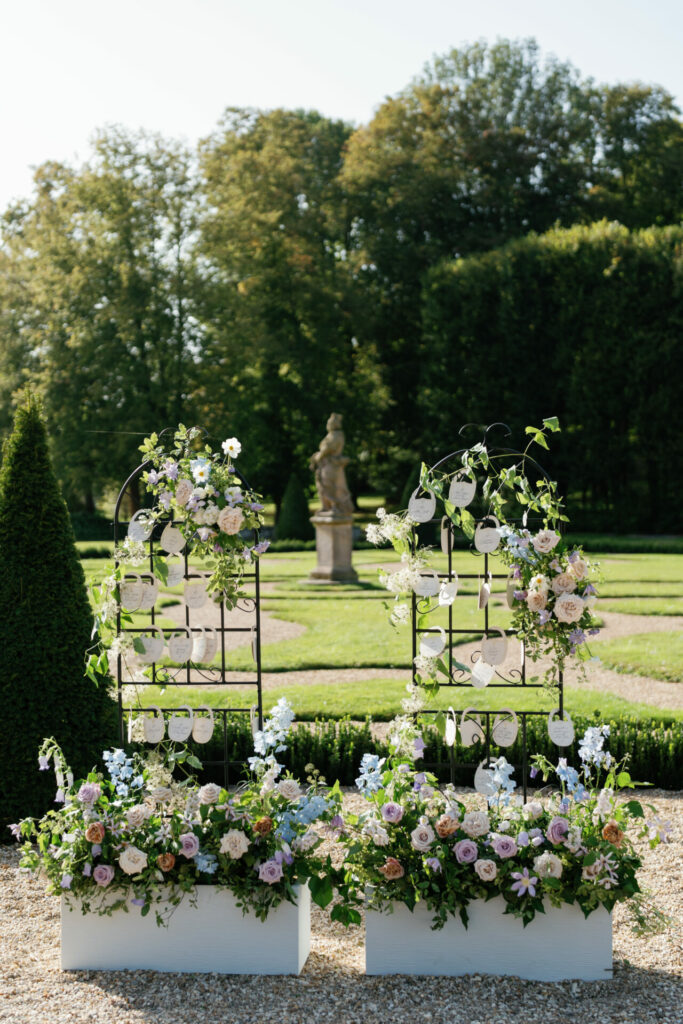Ornate stands with florals, cards in sunny garden.