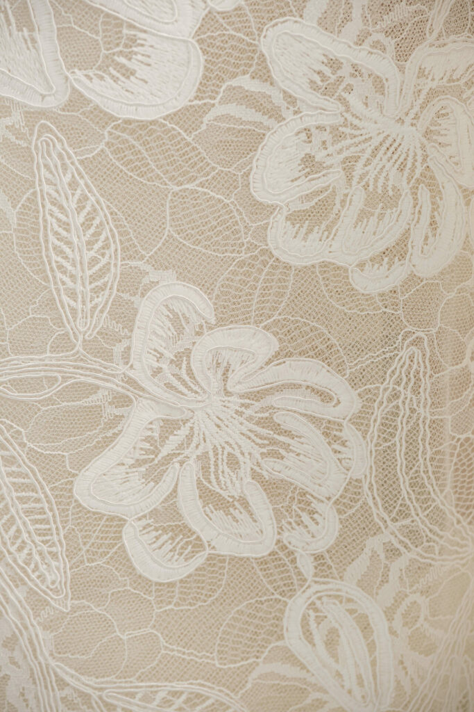 Nera beige lace with white floral embroidery close-up.