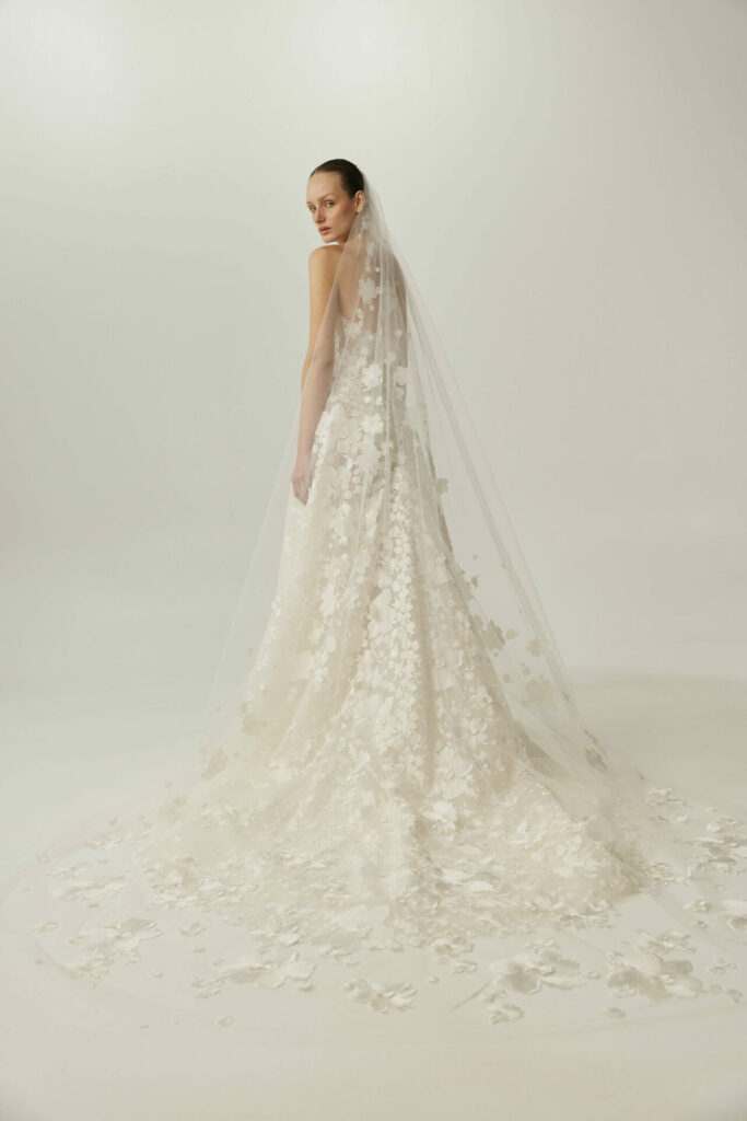Woman in floral white wedding dress, looking back.