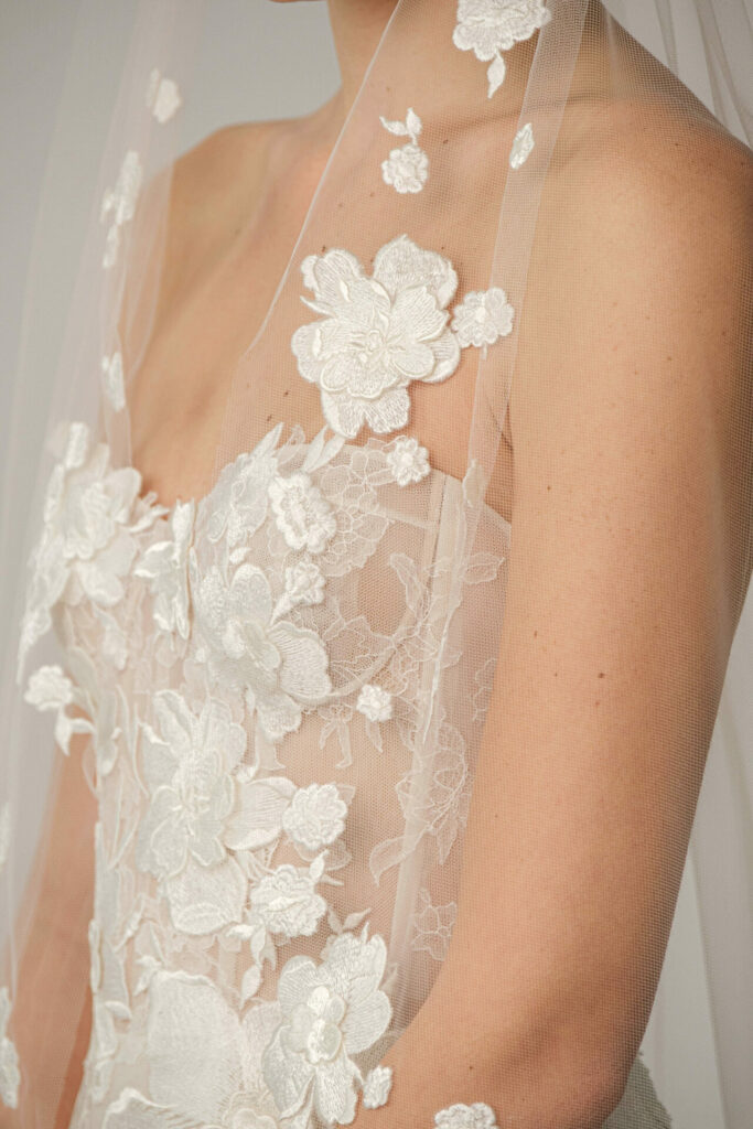 Woman in strapless floral lace wedding dress and veil.