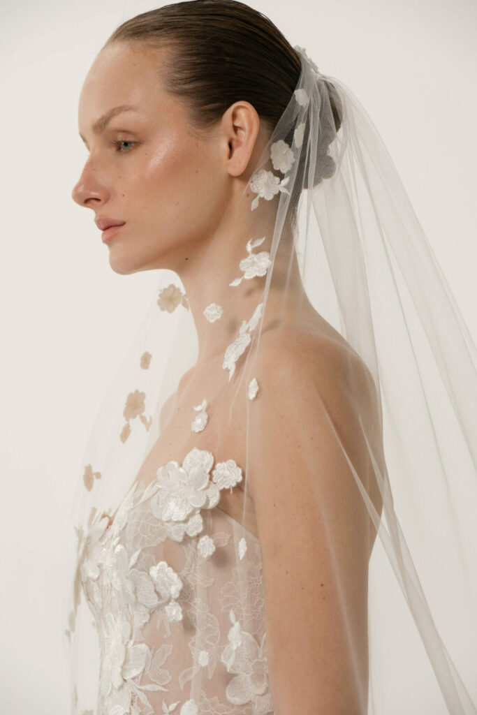 Serina in profile, floral lace wedding dress, veil.