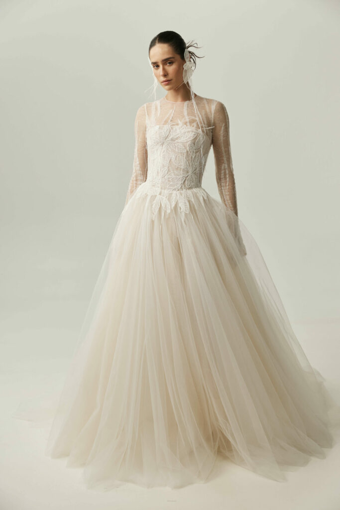 Woman in sheer lace wedding gown, pulled-back hair.