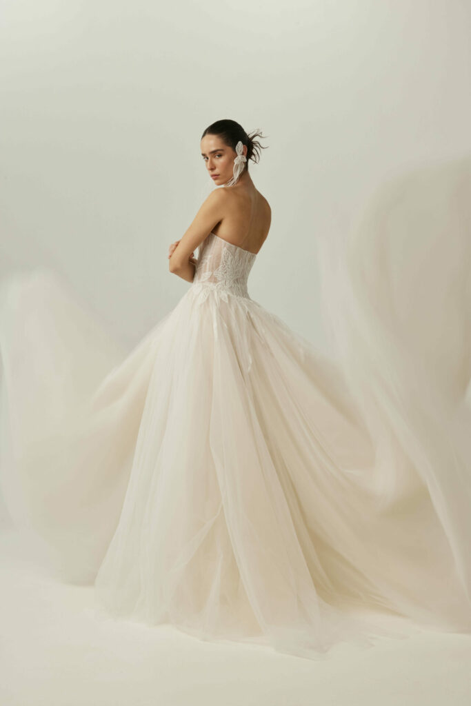 Woman in strapless white gown, hair slicked back.