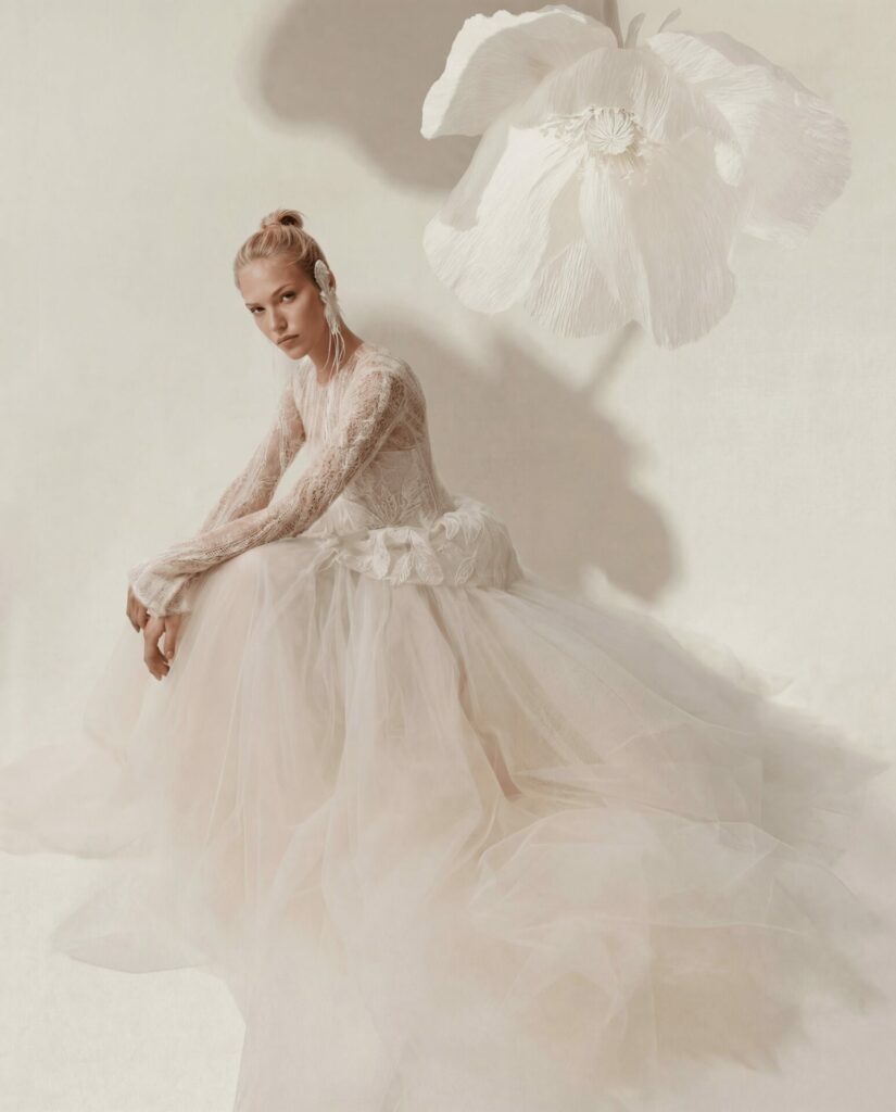 Ena in sheer gown, flower floating overhead, serene.