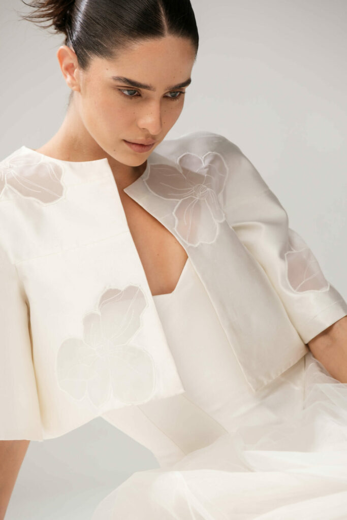 Woman in cream Loie outfit with floral appliqués.