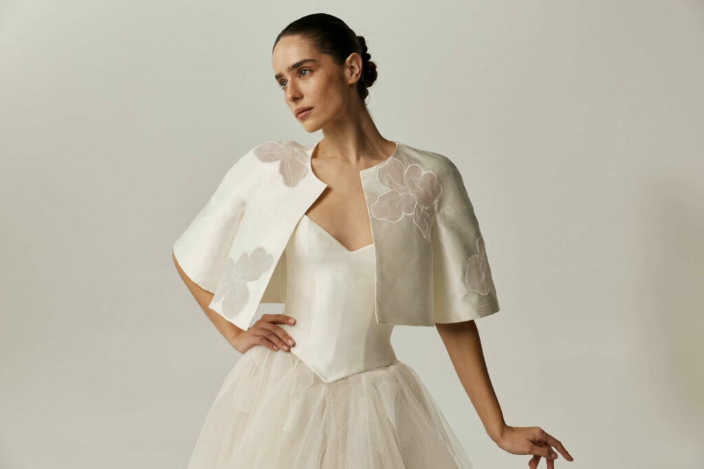 Woman in white strapless gown and cape, posing.