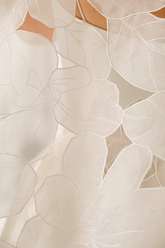 Sheer white fabric with large embroidered floral patterns.